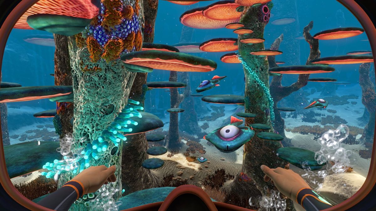 View from a submersible cockpit onto a colorful alien reef, with a creature swimming nearby
